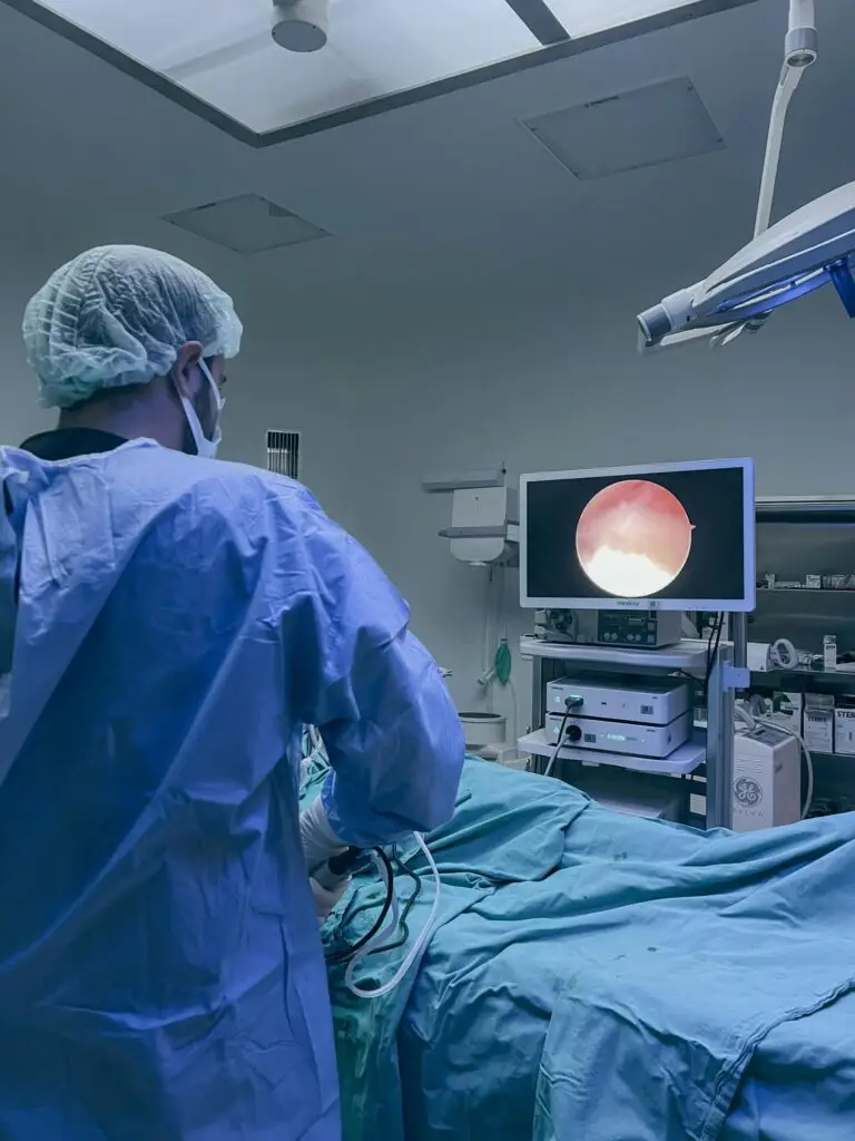 Surgeon in protective clothing performing endoscopic surgery in a hospital operating room.